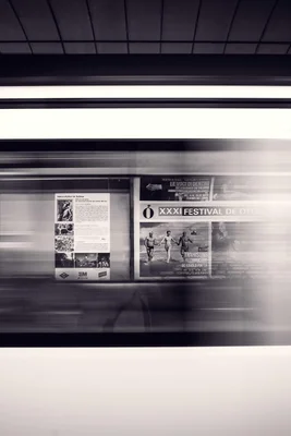 Schwarz-Weiß-Foto von Werbeplakaten in einer U-Bahn, aufgenommen in Bewegung.