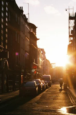 Eine Straßenszene mit geparkten Autos und einer Person im goldenen Licht der Abendsonne.